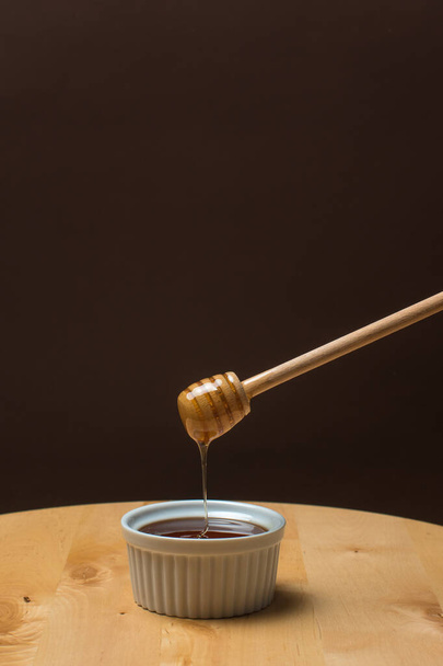 A hand holding a wooden spoon with dripping honey - Fotó, kép