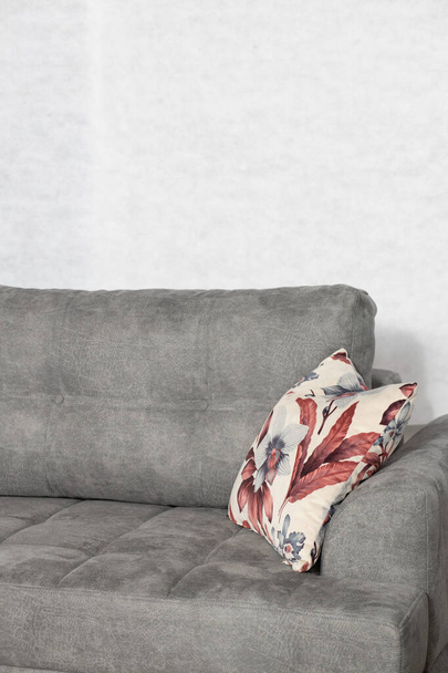 A vertical shot of a grey, modern couch with a pillow in a room - Foto, imagen