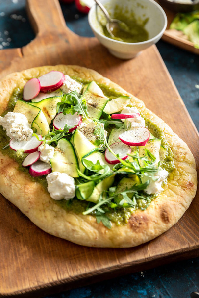 A closeup shot of vegetarian focaccia bread with radish, courgette, rocket, cheese and pesto - Photo, image