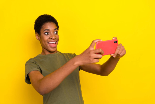 Portrait of funny crazy person hold telephone play video games isolated on yellow color background. - Fotó, kép