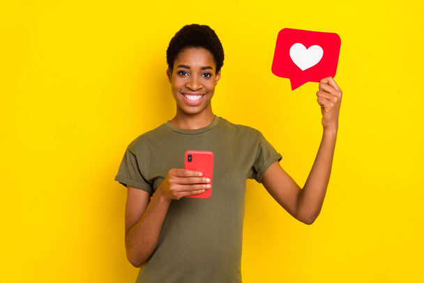 Portrait of positive person hold telephone paper like card toothy smile isolated on yellow color background. - Фото, зображення