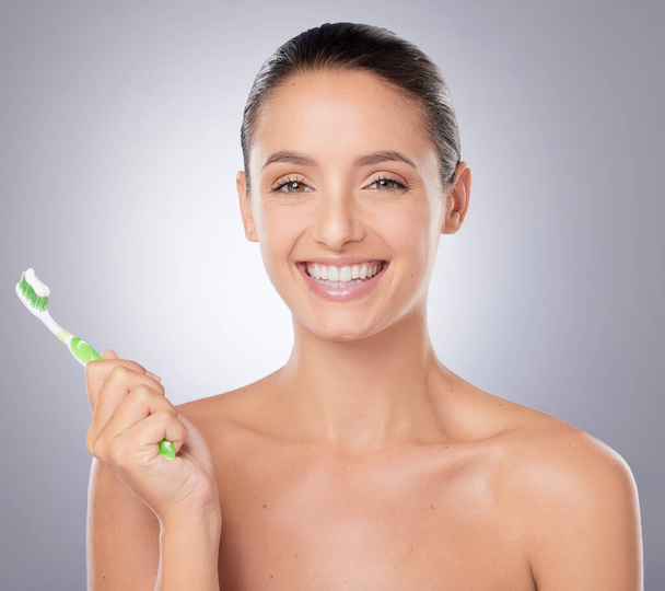 Keeping her smile bright. a beautiful young woman brushing her teeth against a grey background - Photo, image