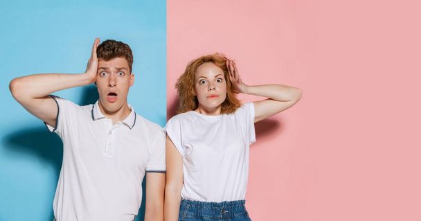 Portrait of young emotive couple posing with shocked expression isolated over pink blue studio background. Big sales. Concept of youth, emotions, facial expression, love, relationship. Poster, ad - 写真・画像