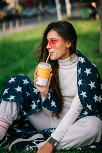 ritratto di una giovane donna attraente nel parco con un bicchiere di carta di caffè. Riposo nel parco - Foto, immagini