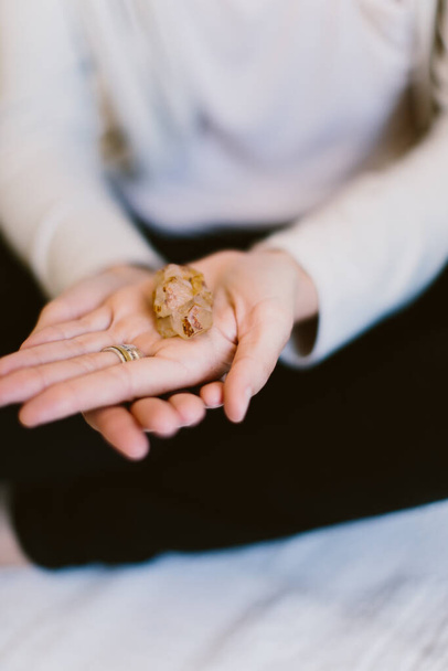 A vertical close-up shot of a woman's hands holding a crystal. - Fotó, kép