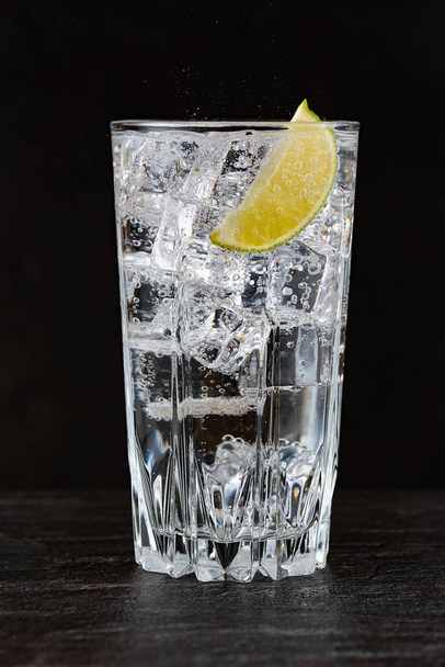 Gin and tonic with ice and lime on dark background - 写真・画像
