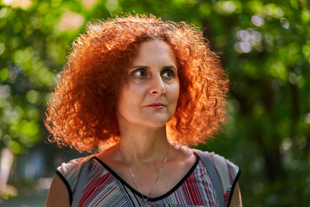 Closeup portrait of a curly readhead woman in the park - Foto, Imagen