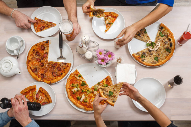 Friends eat pizza together. Group of people at the table eating Italian food. Top view flat lay. - Foto, immagini