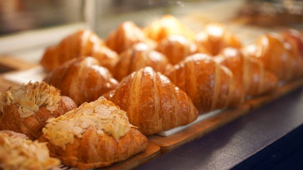 Row of croissants are on plate. Croissant is a buttery, flaky, French pastry. This bread uses the French yeast-leavened laminated dough. Crispy and yummy group frech pastry as fresh bake in group - Foto, Imagen