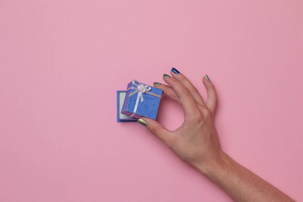 A hand opening a small purple present box in a pink background - Φωτογραφία, εικόνα
