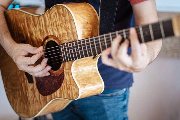A closeup shot of a person playing a brown acoustic guitar - Fotografie, Obrázek