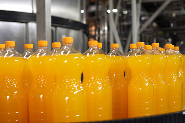 Szénsavas italok gyártása. Narancssárga palackok a gyártósoron - Fotó, kép