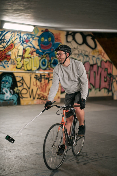Gdansk, Pomeranian Voivodeship, Poland, Europe 07.27.2022. Man playing urban bike polo. Cyclist hittings the ball with mallets. Sport lifestyle concept. - Фото, зображення