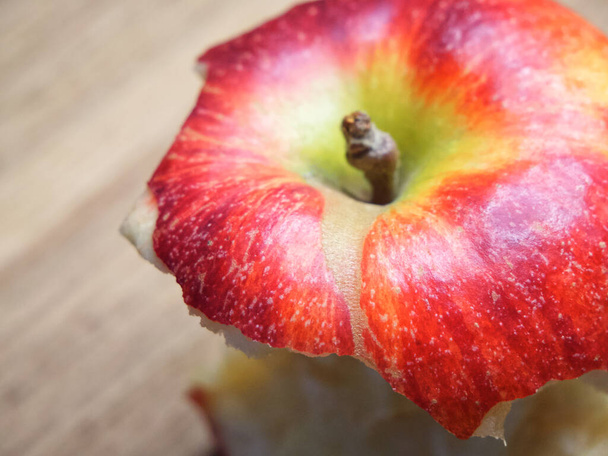Red apple core on a wooden background. A bitten apple close-up. - Fotoğraf, Görsel