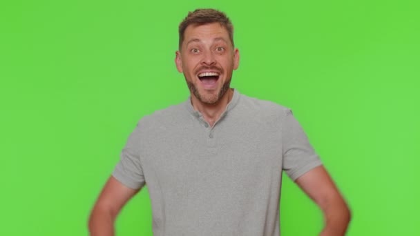 Happy handsome young man shouting, raising fists in gesture I did it, celebrating success, winning, birthday, lottery goal achievemen. Adult guy isolated on green chroma key studio background indoors - Metraje, vídeo