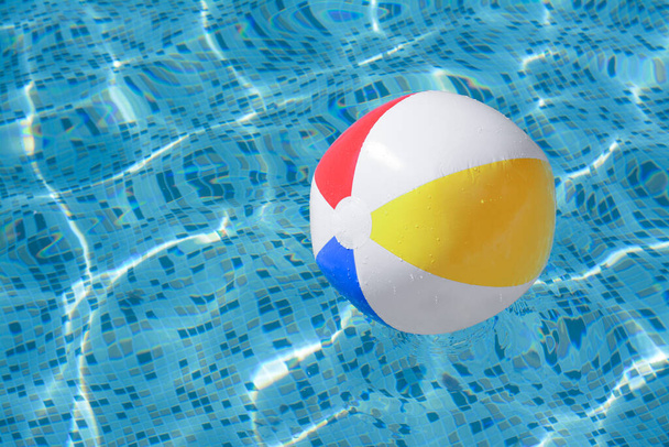 Inflatable beach ball floating in swimming pool, space for text - Foto, Imagen