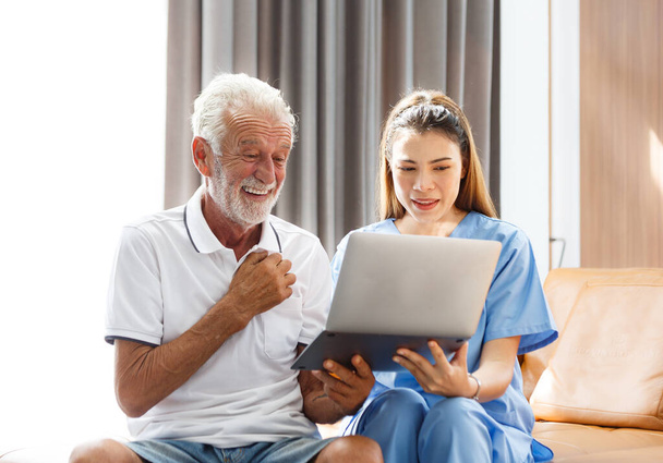 professional female doctor using a laptop computer Medical test results, senior male patients, explain prescriptions using the app. sitting on the sofa at home Elderly health care technology concept - Photo, image