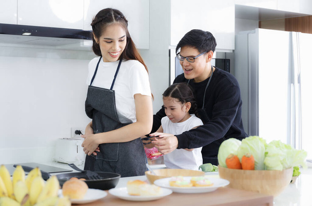 cute father and daughter Help tie the apron rope for mom. to cook home kitchen counters spend time together Just having a fun smile Concept of happy family relationship, lifestyle, couple - Foto, Bild