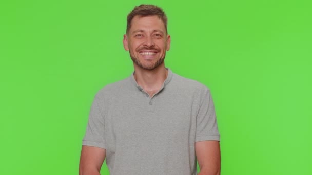 Portrait of happy bearded handsome young man in gray t-shirt looking at camera, smiling. Adult stylish male guy isolated alone on green screen chroma key studio background indoors. Male nature beauty - Footage, Video