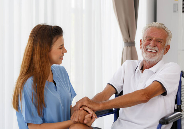 female doctor helping care holding hands to encourage talk Caucasian older man, older adult, patient in a wheelchair at nursing ward health concept Help restore aging, medical and retirement. - Photo, Image