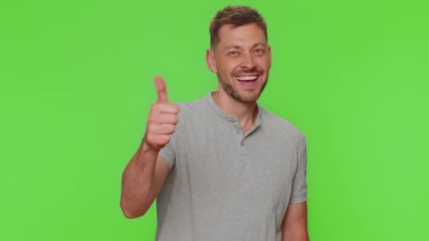 Like. Bearded handsome young man raises thumbs up agrees with something or gives positive reply recommends advertisement likes good. Adult guy isolated alone on chroma key studio background indoors - Filmati, video
