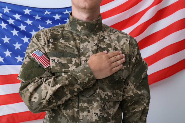 Soldier holding hand on heart near United states of America flag on white background, closeup - Foto, afbeelding