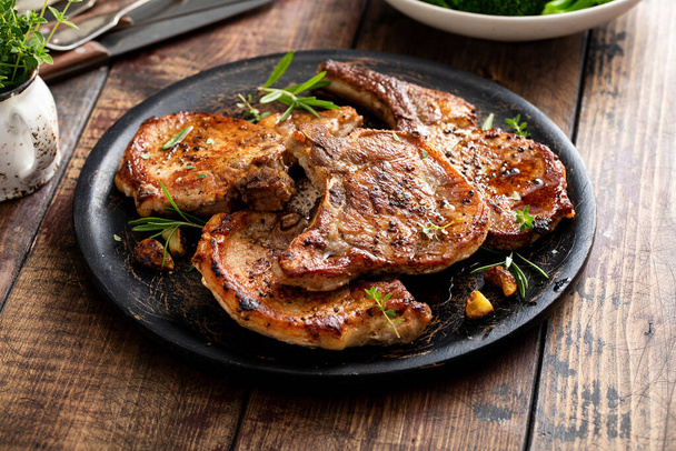 Grilled or pan fried pork chops on the bone with garlic and rosemary - Foto, Imagen