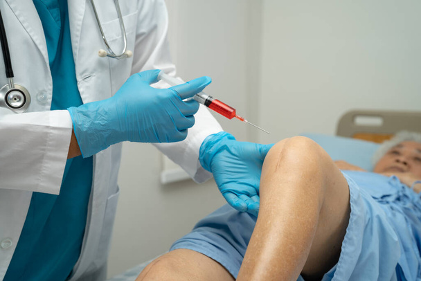 Médico asiático inyectar plasma rico en plaquetas de ácido hialurónico en la rodilla de la mujer mayor para caminar sin dolor. - Foto, Imagen