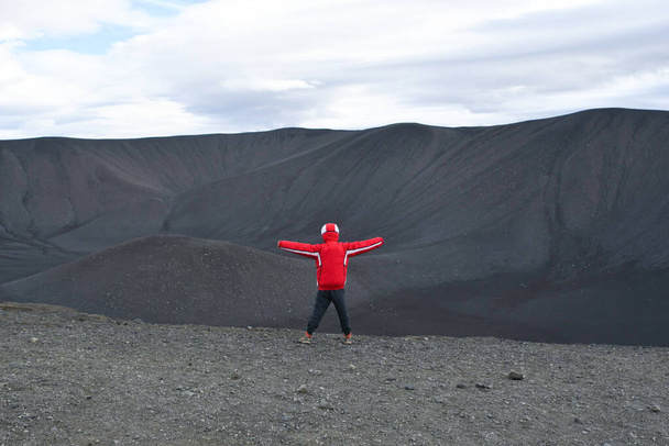 Back of a boy wearing a red jacket on the black earth of a long-extinct volcano Iceland Europe Artic Circle - Foto, afbeelding