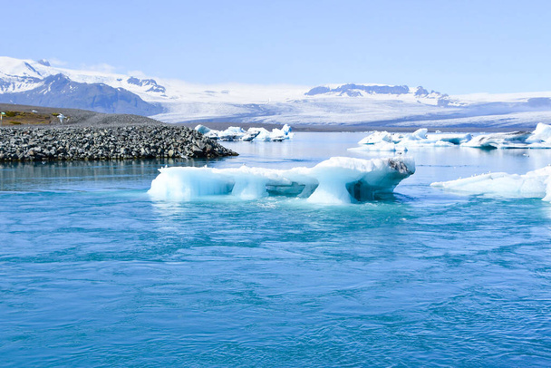 Jotkut jäävuoret liikkuvat kohti merta lumisilla vuorilla taustalla Islanti Euroopassa - Valokuva, kuva