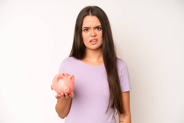 hispanic pretty woma looking shocked, scared or terrified, covering face with hand. piggy bank savings concept - Foto, Imagem