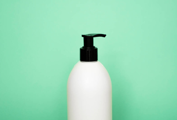 White plastic soap dispenser pump bottle isolated on green background. Skin care lotion. Bathing essential product. Shampoo bottle. Bath and body lotion. Fine liquid hand wash. Bathroom accessories - Foto, Bild