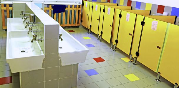 salle de bain d'une pépinière avec lavabos blancs et portes de toilettes jaunes
 - Photo, image