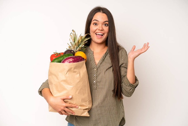 hispanic pretty woma feeling shocked and scared. market vegetables bag concept - 写真・画像