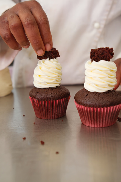 Chef van het gebakje versieren chocolade cupcakes - Foto, afbeelding