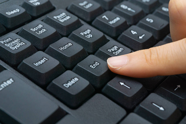 A woman's finger holding a computer keyboard - Фото, изображение