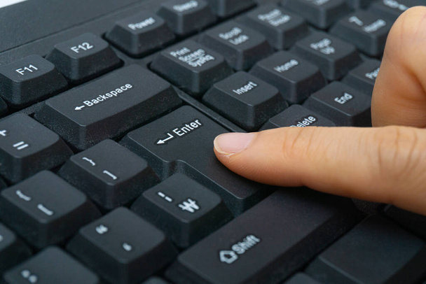 A woman's finger holding a computer keyboard - Fotó, kép