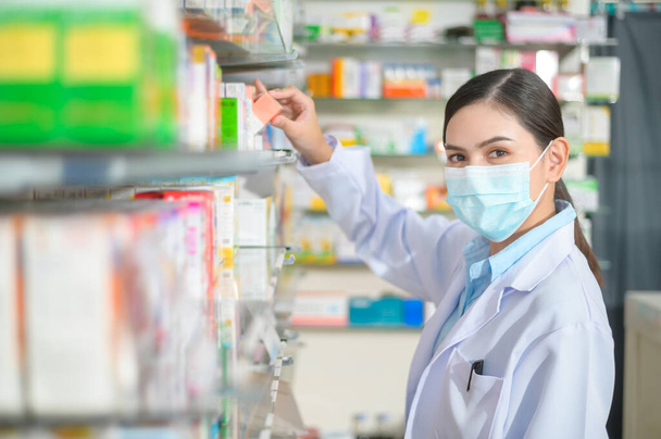 A Portrait of female pharmacist wearing face mask in a modern pharmacy drugstore. - Foto, afbeelding