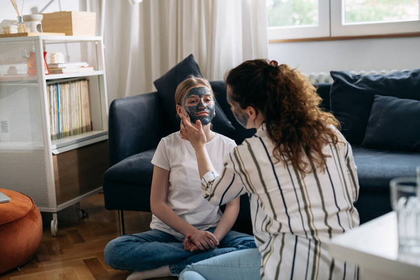 caucasian mother applying cosmetic face mask to her daughter's face - Foto, afbeelding