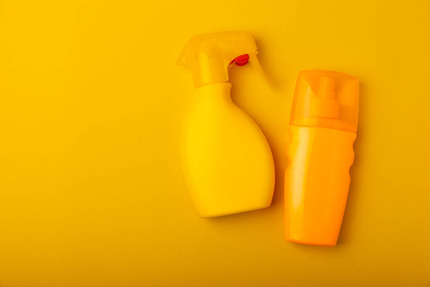 Sunscreen on a yellow background. Plastic bottle of SPF sunscreen. Sunscreen selection.Summer travel beach flat lay composition, banner. Summer vacations and spf uv-protecting skin care concept. - Foto, afbeelding