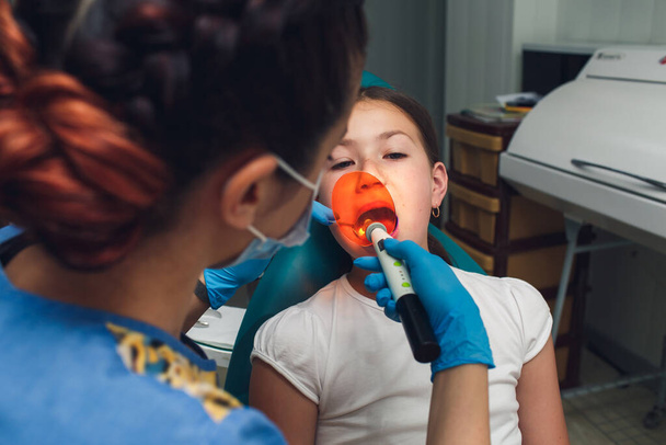 Dentist working with dental polymerization lamp in oral cavity. - Foto, Bild