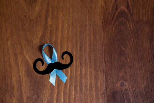 Blue prostate cancer awareness ribbon with a moustache on a rustic wooden table.  - Foto, Imagem
