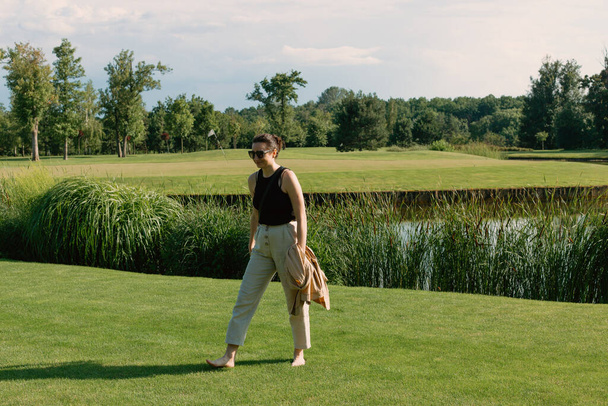 Красива дівчина гуляє босоніж на зеленій траві в парку в сонячний день
 - Фото, зображення