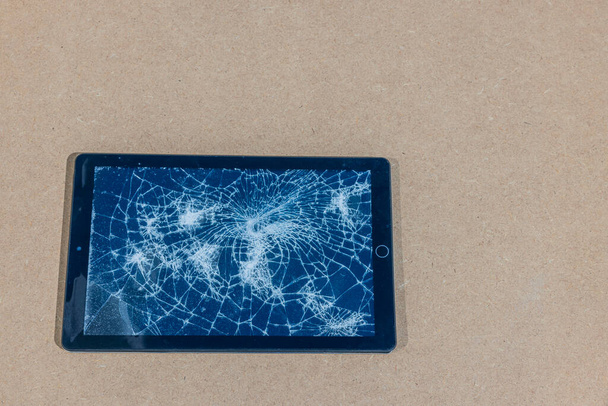 Close-up weergave van elektronische tablet met beschadigd scherm geïsoleerd op grijze achtergrond.  - Foto, afbeelding