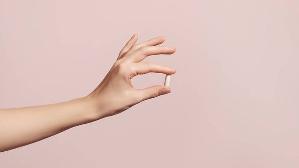 Hand holding the supplements on pink background. High quality photo - Foto, imagen