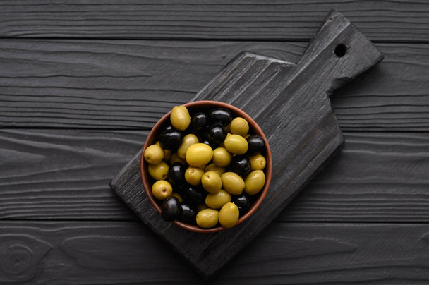 Black and green olives on a dark wooden black background. - Valokuva, kuva