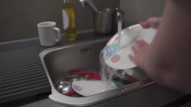 Крупним планом домогосподарка миє посуд на кухні. Руки жінки миють посуд. Використовуючи мило, людина прибирає посуд. Жіночі руки миють посуд у мийці для кухні. Побутова концепція
 - Кадри, відео