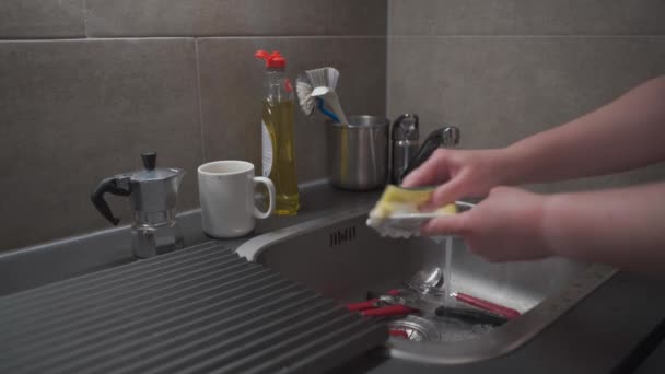 Close-up of a female hand washing kitchen sink utensils at home in the kitchen and using cleaning fluid. The theme is housekeeping and household chores. House clean-up, household routine. Housework - Πλάνα, βίντεο