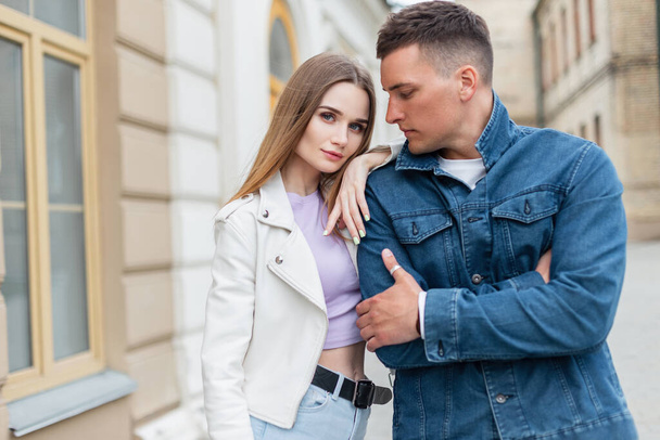 Beautiful trendy young stylish models couple woman and man in fashionable street denim clothes are walking near a vintage building in the city - Foto, imagen