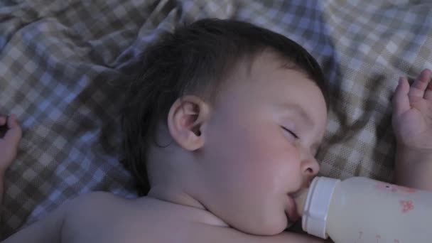 Nukkuvan lapsen muotokuva pullo suussa. Vauva syö unessa. Vauva juo maitoa pullosta ja nukkuu. Laadukas 4k kuvamateriaalia - Materiaali, video